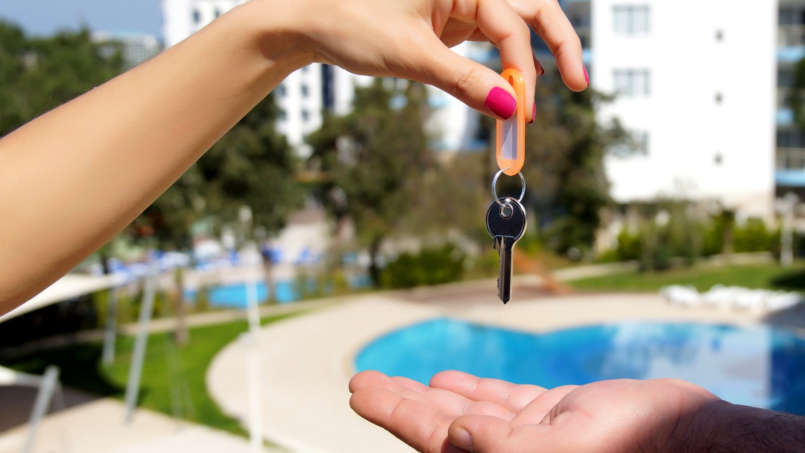 Handing over a rental key in front of a beach condo