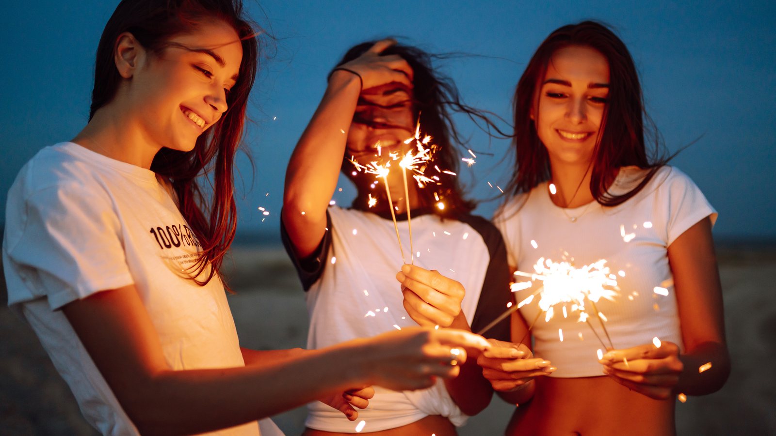 Friends celebrating with sparklers on the beach at night